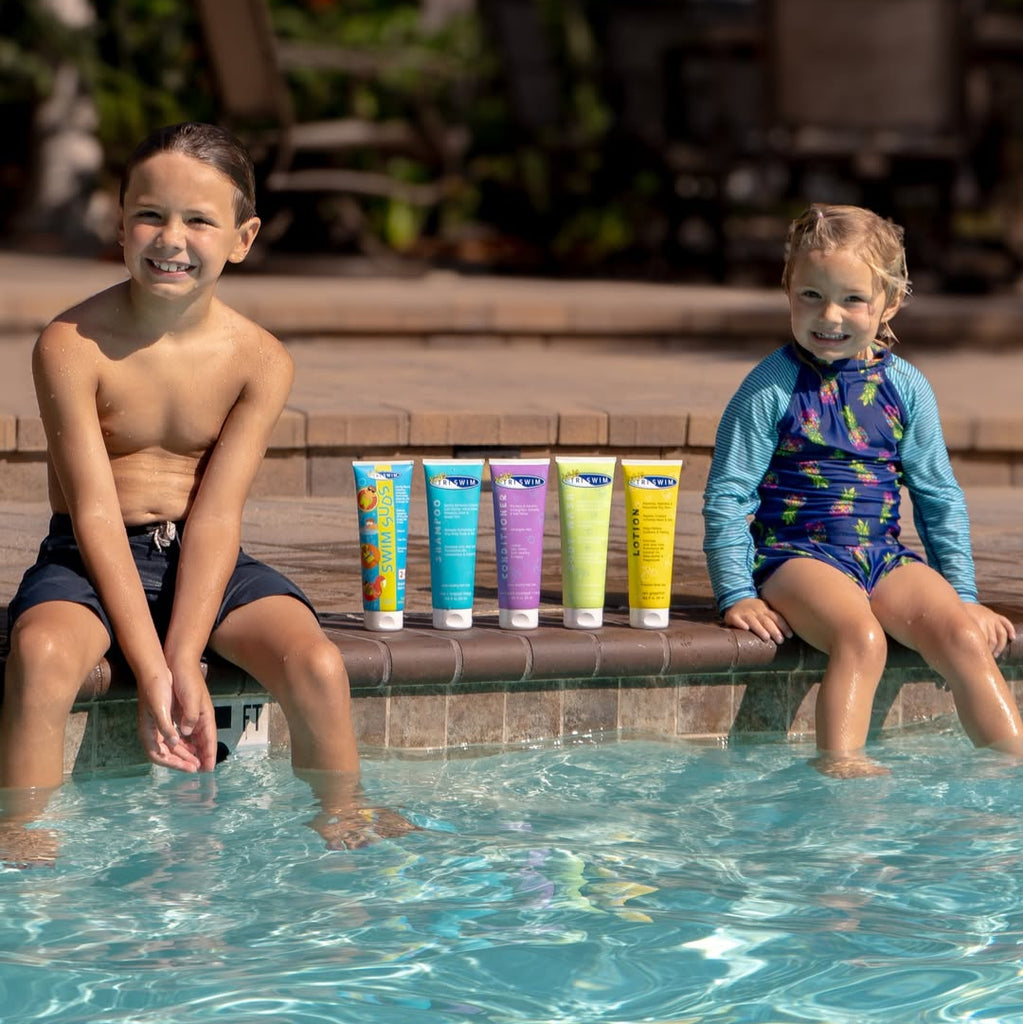 Two children sitting by a pool with six bottles of TRISWIM hair and skincare formulas next to them.